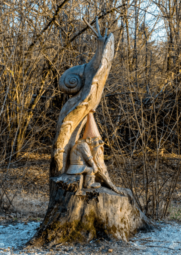 Scultura in legno eseguita da Ezio Giordano di uno gnomo con una chiocciola sopra.